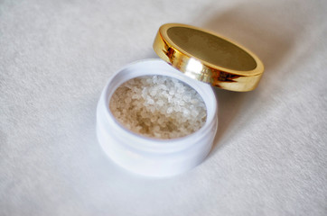 Obraz na płótnie Canvas bath salt crystals in a white jar on a light background