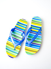 Colorful striped flip flops on white background