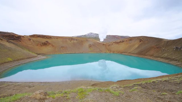 Viti Crater in Krafla caldera geothermal blue green turquoise color colorful lake water and industrial smoke steam vapor wide angle landscape from power plant