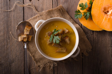 Pumpkin soup and organic pumpkins on wooden table. Seasonal autumn food - Spicy pumpkin soup in bowl.