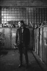A man in a suit and coat poses for advertising men's clothing. Black and white photo. Advertising menswear