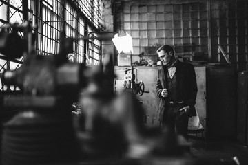 A man in a suit and coat poses for advertising men's clothing. Black and white photo. Advertising menswear