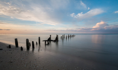 Long exposure shot sunset seascape with mortar of broken bridge.