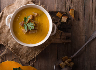 Pumpkin soup and organic pumpkins on wooden table. Seasonal autumn food - Spicy pumpkin soup in...