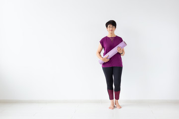 Yoga, people concept - Portrait of a middle age woman after yoga with her mat on white background with copy space