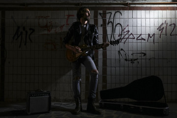 A street musician playing on guitar in the underpass. Vagrant lifestyle. Playing in the underpass...