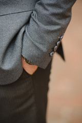 A man with a beard and sunglasses in a gray suit poses on the street to advertise men's clothing. Advertising menswear