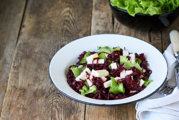 Beet salad with cheese and lettuce in a white bowl