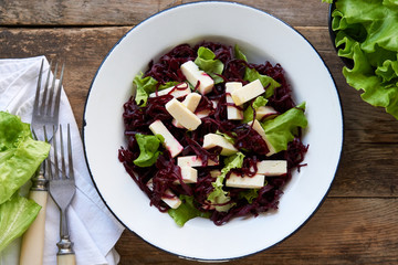 Beet salad with cheese and lettuce in a white bowl