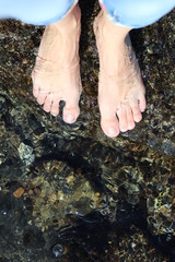 feet close up stand on a stone in the sea