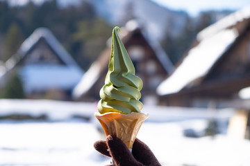 Hand holding Soft green tree ice cream with snow background