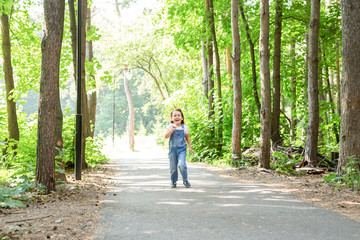 Children, childhood and nature concept - Portrait of beautiful small child girl running through the park