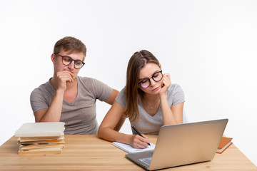 Education, people and relationship concept - a couple of students are tired of doing homework