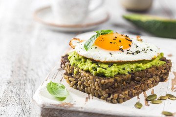 Sandwich with avocado, egg and spinach on white wooden background. Healthy diet breakfast