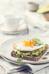 Sandwich with avocado, egg and spinach on white wooden background. Healthy diet breakfast