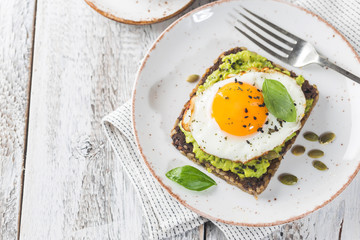 Sandwich with avocado, egg and spinach on white wooden background. Healthy diet breakfast