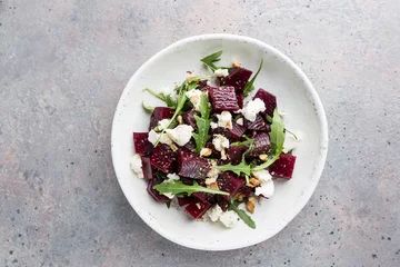 Poster beetroot salad with blue cheese, arugula and walnut in a white plate on gray background, top view © petrrgoskov