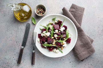 beetroot salad with blue cheese, arugula and walnut in a white plate on gray background, top view