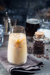 Ice coffee cold summer drink in a tall glass and coffee beans on a stone background.