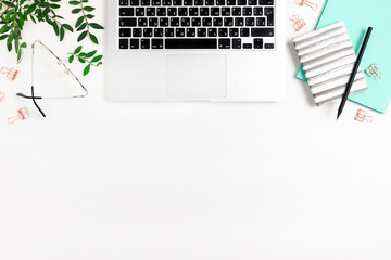 Workspace with laptop, notepads, pistachios branches, glasses, stationery