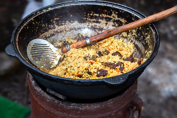 Cooking traditional Uzbek pilaf in a large cauldron