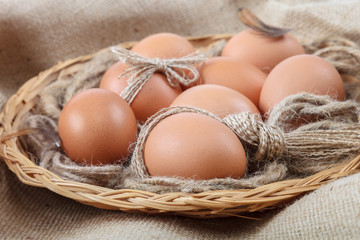 Chicken eggs in a wicker basket on canvas
