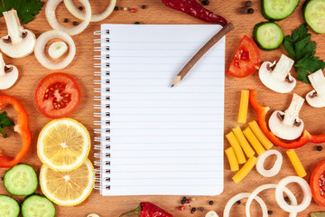 Set of sliced vegetables and fruits, with spices and a cookbook on a cutting board.