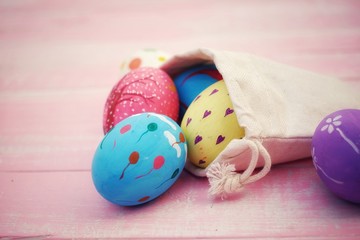 Colorful hand painted easter eggs with pink distress wooden background, pastel color eggs, each...