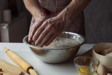 A handful of flour with egg on a rustic kitchen. Against the background of men's hands