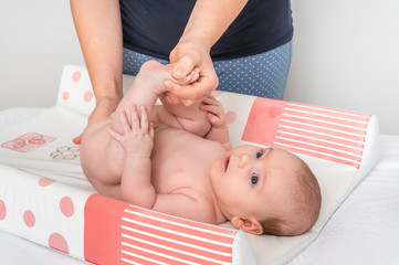 Mother is changing diaper to her little baby