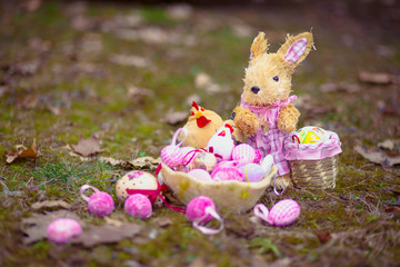 Easter bunny toy and basket with colored eggs and yellow chick toy on the grass. Easter concept