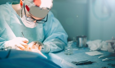 young male surgeon operates a patient in the operating room. medical concept