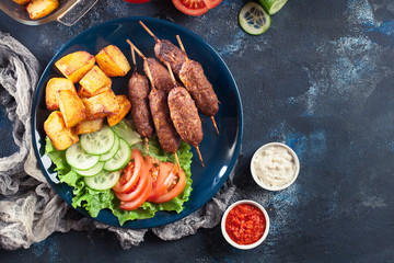 Grilled shish kebab served with fried potatoes