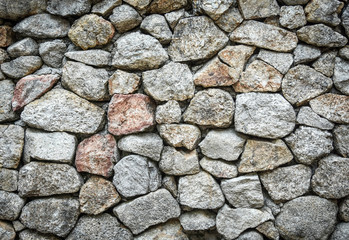 Textured background of rough grey stone wall.