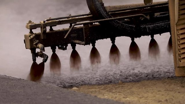Machine sprays bitumen on the new road. Asphalt