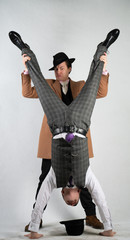 two friends dressed in vintage clothes in classic style and stand upside down and fool around on a...