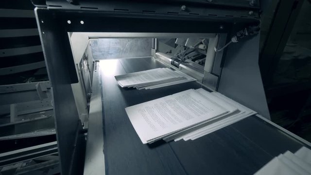 Stacks of paper with printed text are moving along the conveyor belt