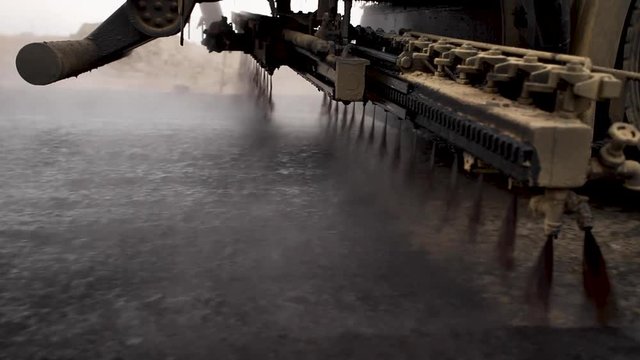 Machine sprays bitumen on the new road. Asphalt