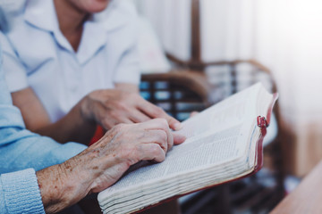Close up of old woman and her friends hold and reading bible together at home