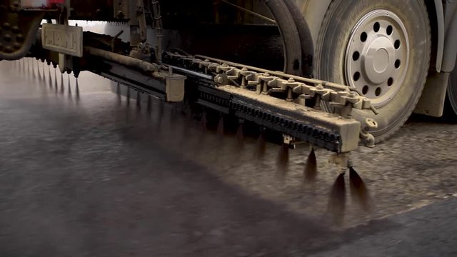 Machine sprays bitumen on the new road. Asphalt