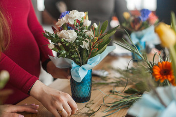Women on the master-class on floristics. Young ladies making floral composition. Group of females with flowers indoor at the loft background. Decoration process.