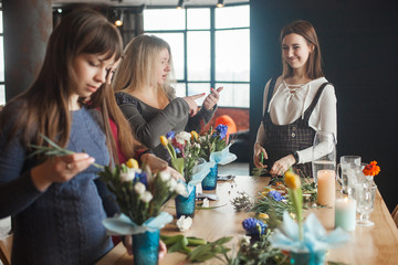 Women on the master-class on floristics. Young ladies making floral composition. Group of females...