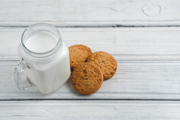 Milk with cookies on wooden white background