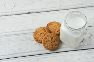 Milk with cookies on wooden white background
