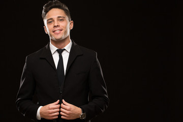 Sexy handsome suited young man smiling seductively to the camera on black background copyspace temptation masculinity manly macho boyfriend positivity confidence power businessman flirty