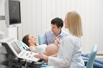 Obraz premium Pregnant woman with husband on ultrasound exam.