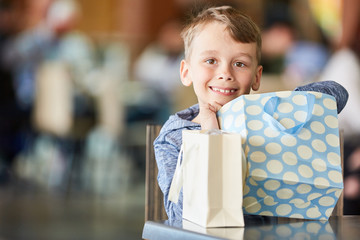 Junge beim Shopping packt eine Tüte aus