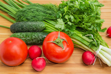 Fresh vegetables and greens on bamboo cutting board close-up