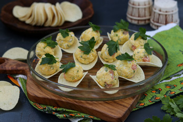 Appetizer on chips with salmon, eggs and cheese