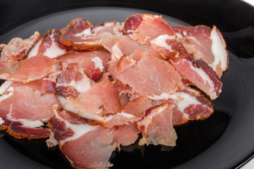 Thin slices of dried pork neck on black dish